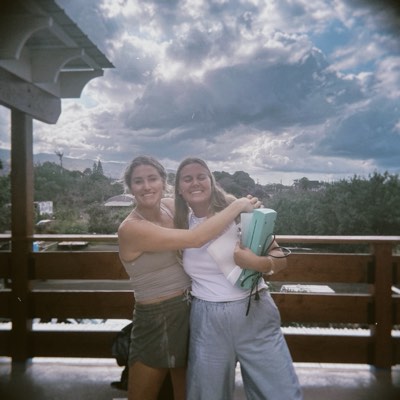 Maddie and Chelsey on the deck after class, arms around each other, speaker in hand